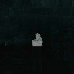 person in white hoodie standing in front of black brick wall