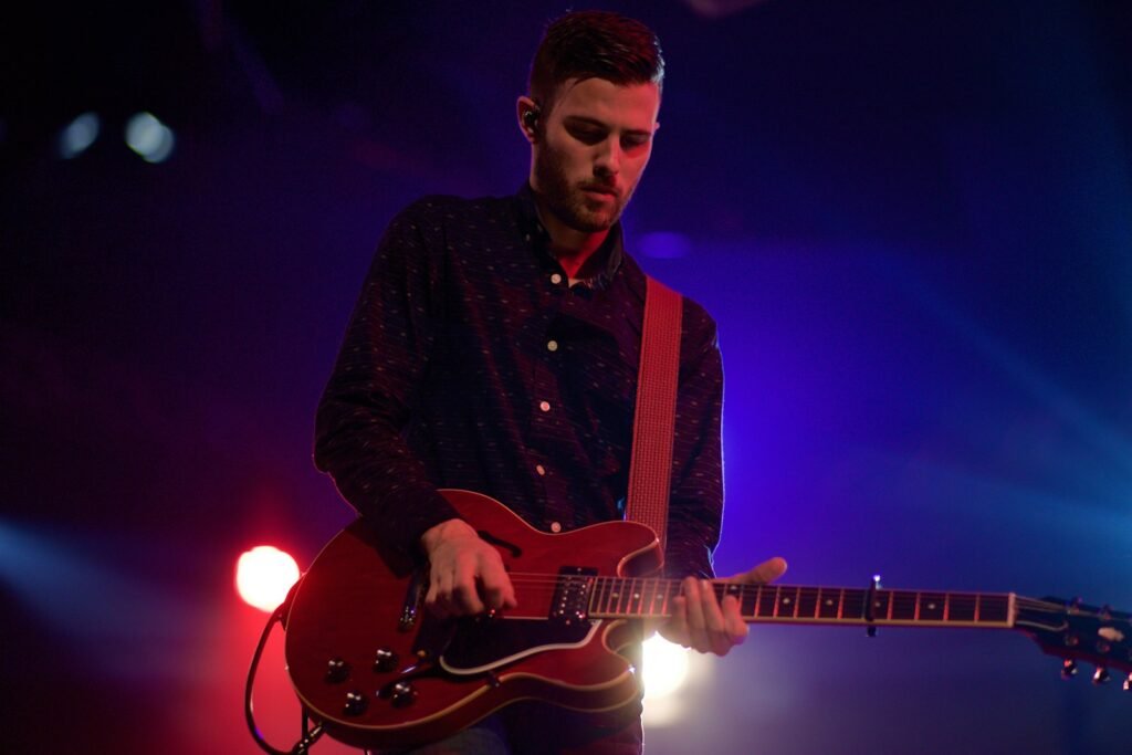 Photo by William White man playing black electric guitar